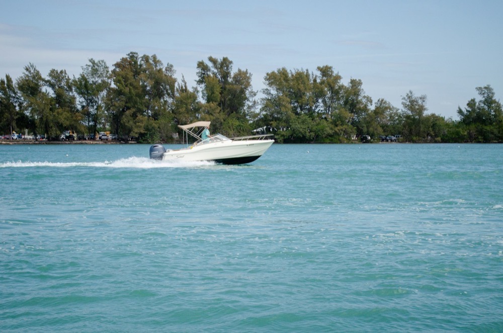 A white bay boat running across clean turquoise water